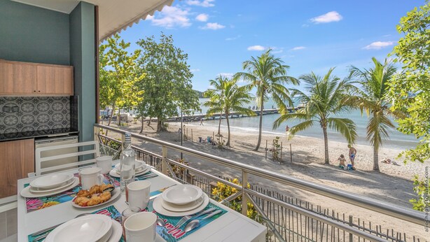 A dining area with a view of the beach and palm trees. - Hôtel Le Courbaril (Trois-Ilets)