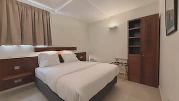 Ein Schlafzimmer mit einem Bett, einem Kleiderschrank, einem Nachttisch und einem Fenster mit Vorhängen.