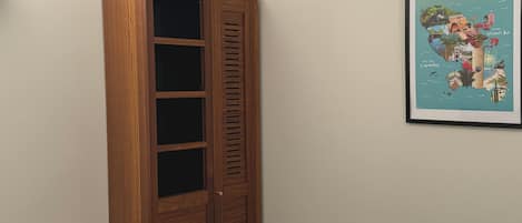 Ein Zimmer mit einem Holfischschrank, einem gerahmten Bild von Martinique und einem Wäscheständer aus Holz.