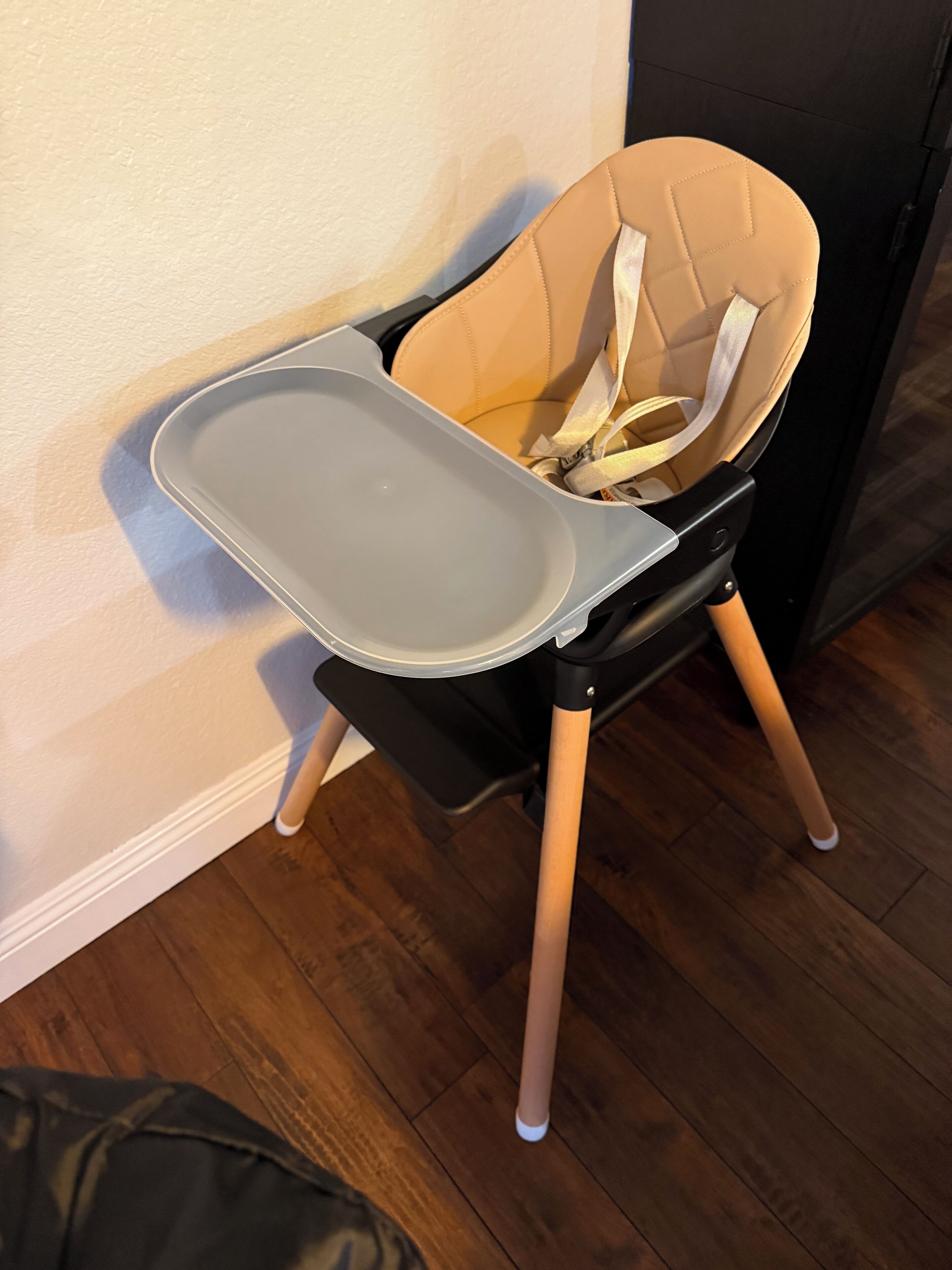 Une chaise haute avec une tablette, placée contre un mur.