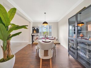 Enjoy meals in this dining area with a long table for four, a potted plant, and a modern kitchen.