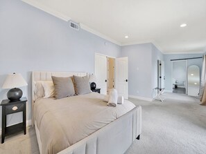 Relax in a serene bedroom with a large bed, nightstand, and door to a separate room.