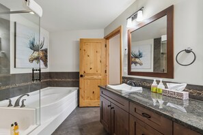 Un baño moderno con una bañera, un espejo grande y una puerta de madera.