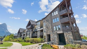 A multi-story hotel with balconies, stone facade, and a mountain backdrop. - Rundle Cliffs Lodge by Canmore Premier  (Canmore)