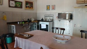 A kitchen with a stove, microwave, and sink. There is a table with a checkered tablecloth and a bowl. - Marisol, spacious and comfortable farm in Araçoiaba da Serra  (Araçoiaba da Serra)