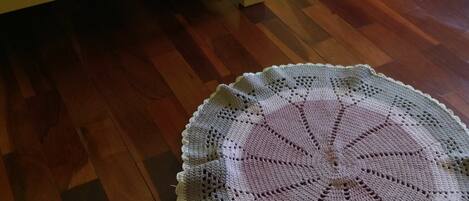 Deux lits en bois avec une literie bleue et blanche, un chemin de table en crochet sur le sol et un tableau au mur.