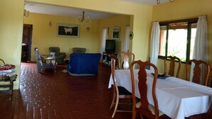 A dining area with a table set for four, a television, and a blue-covered sofa. - Marisol, spacious and comfortable farm in Araçoiaba da Serra  (Araçoiaba da Serra)