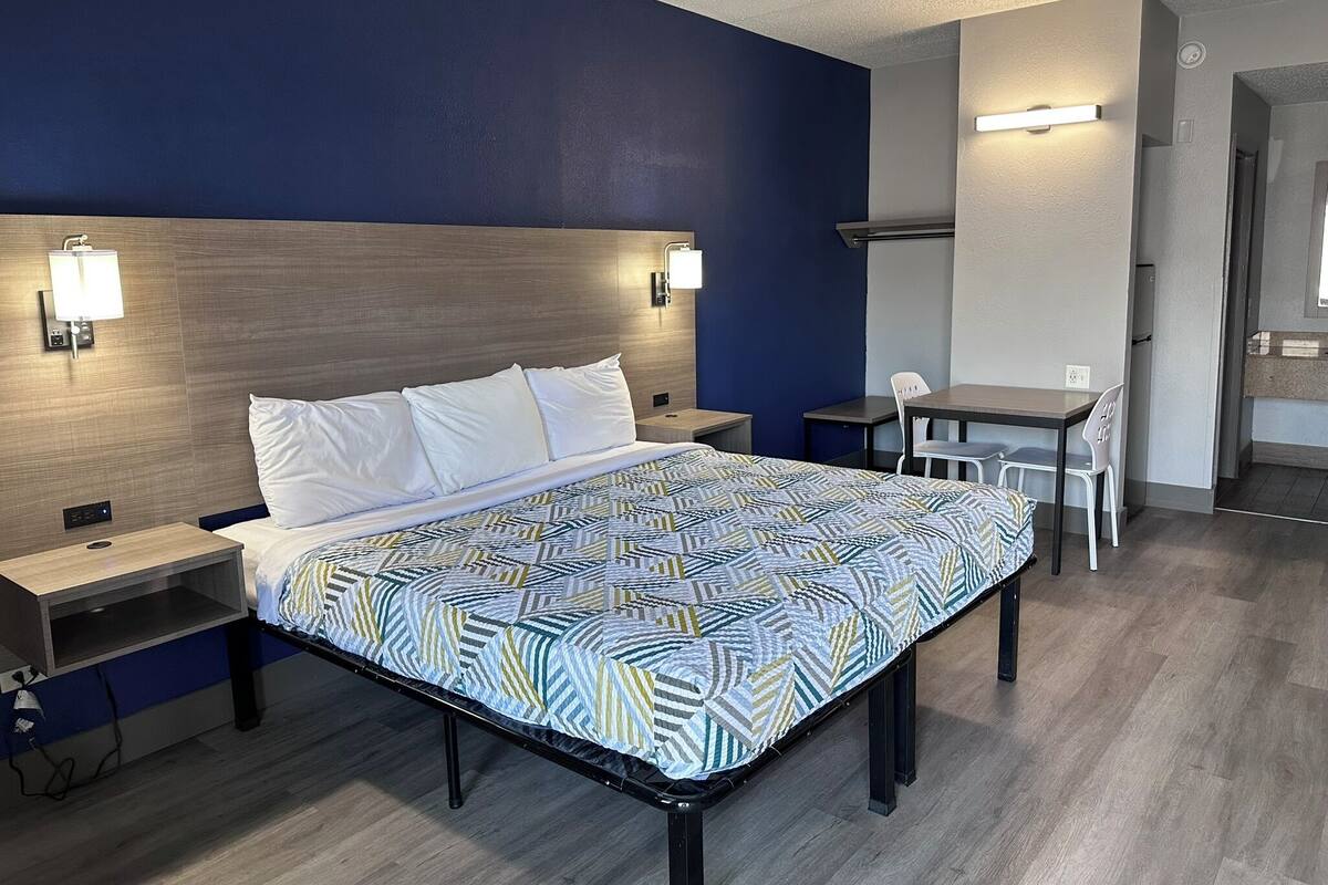 A hotel room with a bed, bedside tables, a desk, and a chair.