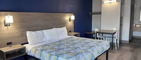 Quarto de hotel com cama, mesas de cabeceira, escrivaninha e uma cadeira.