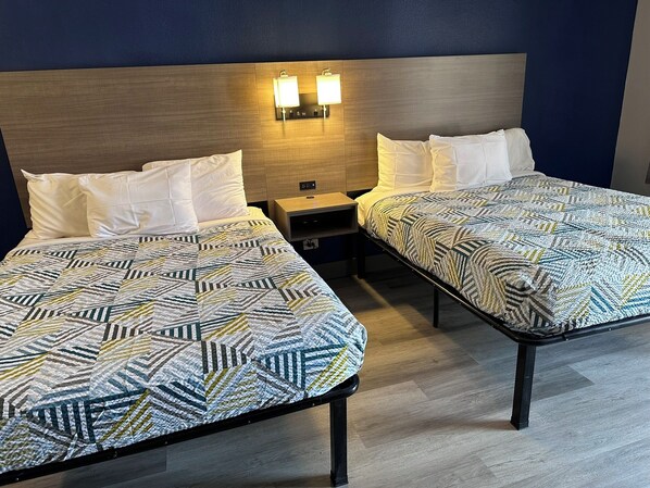 Une chambre d’hôtel avec deux lits, chacun doté d’une couvre-lit à motifs, d’une tête de lit en bois et de lampes fixées au mur.