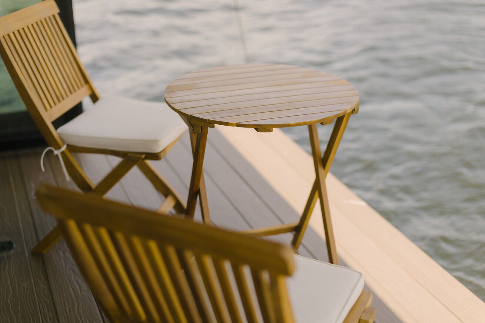 A wooden deck with a round table and two chairs.