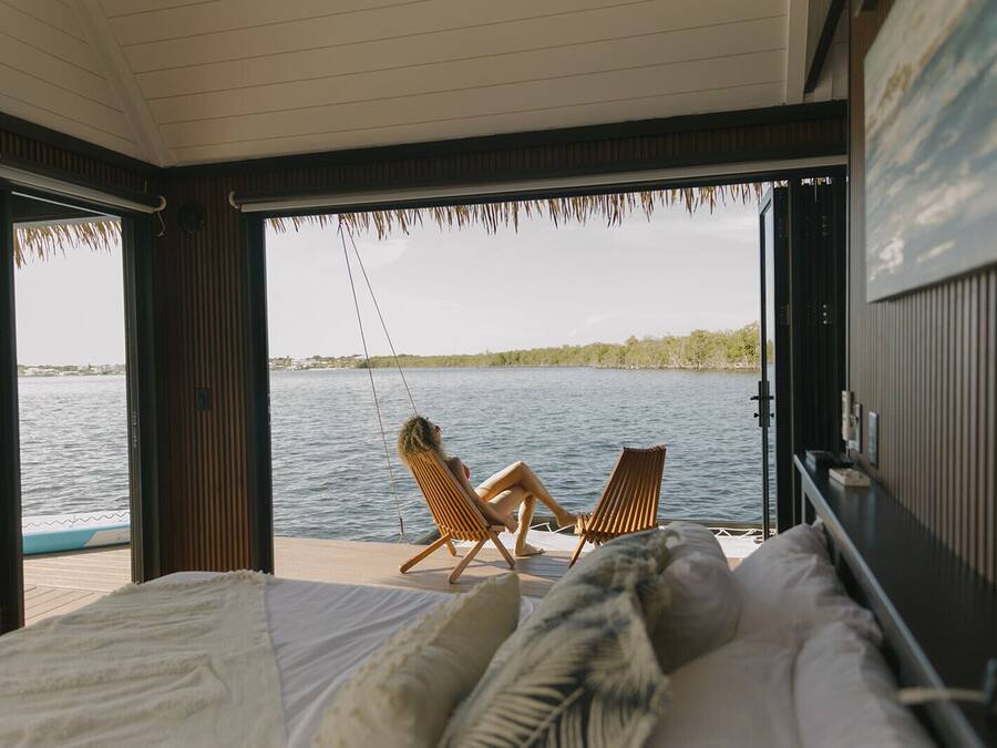 A room with a bed, two chairs, and a view of a lake.