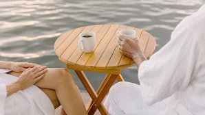 A wooden table with two white cups, one with coffee and one with tea, placed on a body of water. - Premium Floating Bungalow by Stay Ombi (Key Largo)
