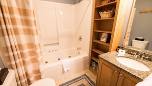 A bathroom with a bathtub, toilet, and vanity with a sink. - Sugarloaf Mountain St John Drive C6001T (Carrabassett Valley)