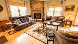 A cozy living room with a stone fireplace, leather sofas, and a wooden coffee table. - Sugarloaf Mountain St John Drive C6001T (Carrabassett Valley)