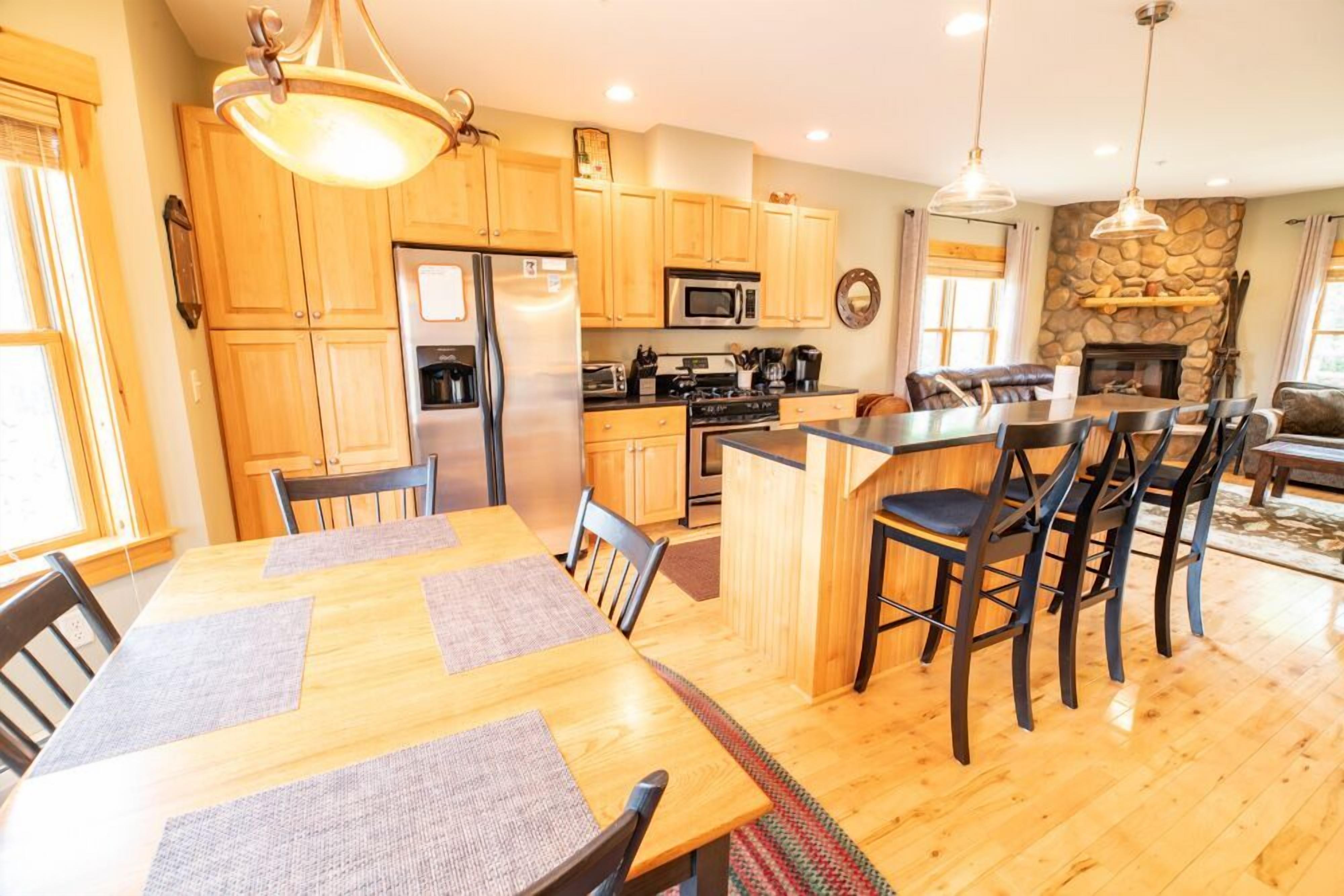 A modern kitchen with wooden cabinets, a central island, and a dining area with a large table and chairs.
