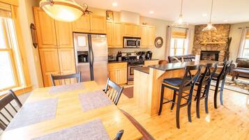 A modern kitchen with wooden cabinets, a central island, and a dining area with a large table and chairs.