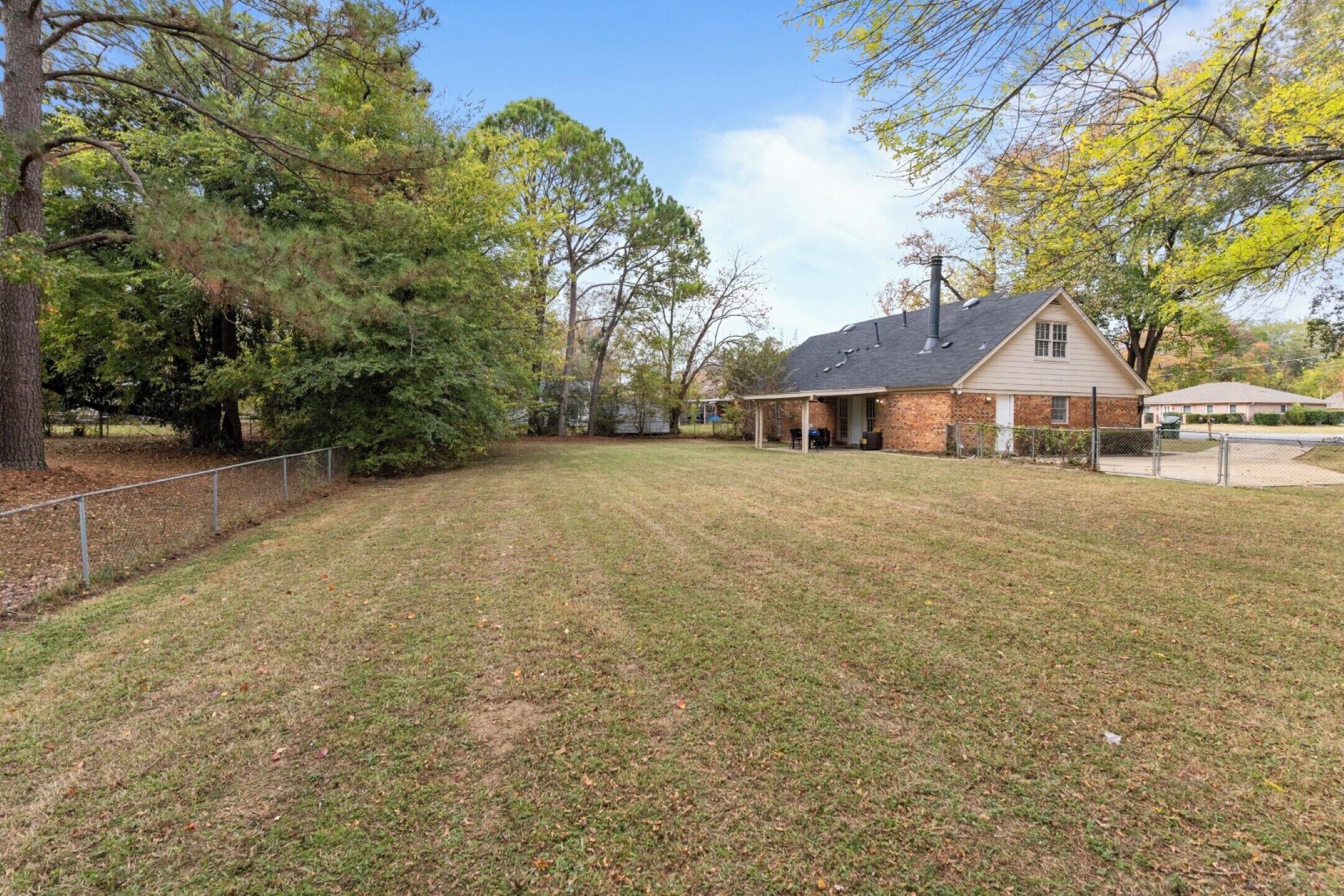 A house with a brick exterior, a covered porch, and a fenced yard.