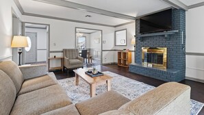 Ein großzügiges Wohnzimmer mit Kamin, einer Sofagarnitur und einem Couchtisch.
