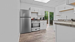 A modern kitchen with white cabinets, stainless steel appliances, and a wooden deck area.