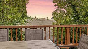 A deck with a view of a building and trees.