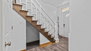 A staircase with white railings and wooden steps, leading to a door with a window above it.