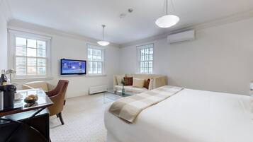 Una habitación de hotel con una cama grande, un escritorio con una silla, un televisor y dos ventanas.