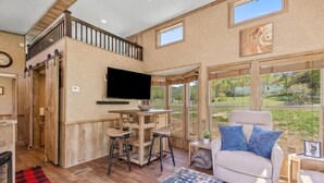 A spacious living area with a large TV, wooden furniture, and a view of the outdoors. - Farm Stay Pool 15min to Chattanooga (Chattanooga)