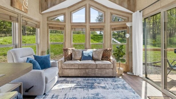 A modern living room with a large window, a sofa, and a coffee table. - Farm Stay Pool 15min to Chattanooga (Chattanooga)