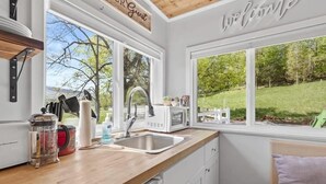 A kitchen with a wooden countertop, white cabinets, a sink, a microwave, and a view of a green landscape through large windows. - Farm Stay Pool 15min to Chattanooga (Chattanooga)