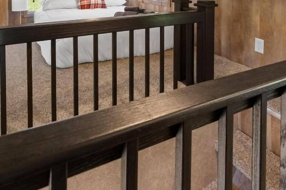 A bedroom with a bed, a window, and a wooden railing.