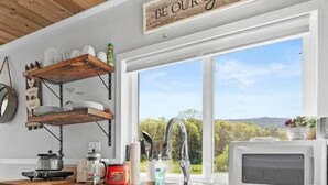 A kitchen with white cabinets, a wooden countertop, a microwave, a sink, and a window with a view of greenery. - Farm Stay Pool 15min to Chattanooga (Chattanooga)