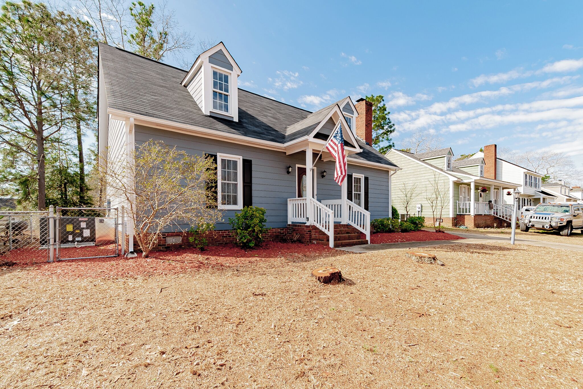 A residential house with a front porch, a flag, and a driveway.