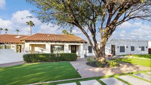 A residential property with a well-maintained lawn, a paved driveway, and a large tree.