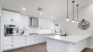 A modern kitchen with white cabinetry, a built-in oven, and a large island with a sink.