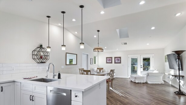A modern kitchen with white cabinetry, a central island, and pendant lighting.