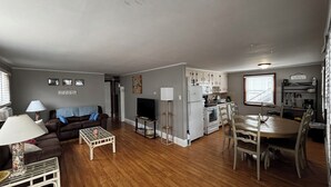 Een ruimtelijke leefruimte met een keuken, eethoek en zithoek.