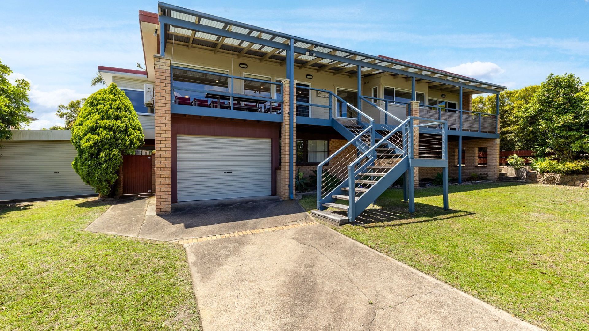 A two-story building with a covered patio, a garage, and a staircase leading to the upper level.