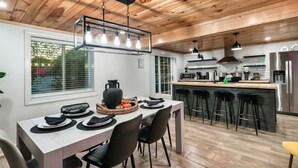 Eine moderne Küche mit Holzbalkendecke, einer Essecke mit Tisch für vier Personen und einer Bar mit Hockstühlen.