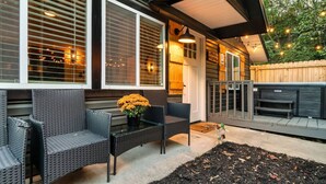 Eine Terrasse im Freien mit Korbmöbeln, einem kleinen Tisch mit Blumenvasen und einem Holzboden.