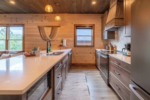 A modern kitchen with wooden walls, a large island, and stainless steel appliances. - New Lux 4 King Suites | GameRm | Hot Tub | Views (Gatlinburg)