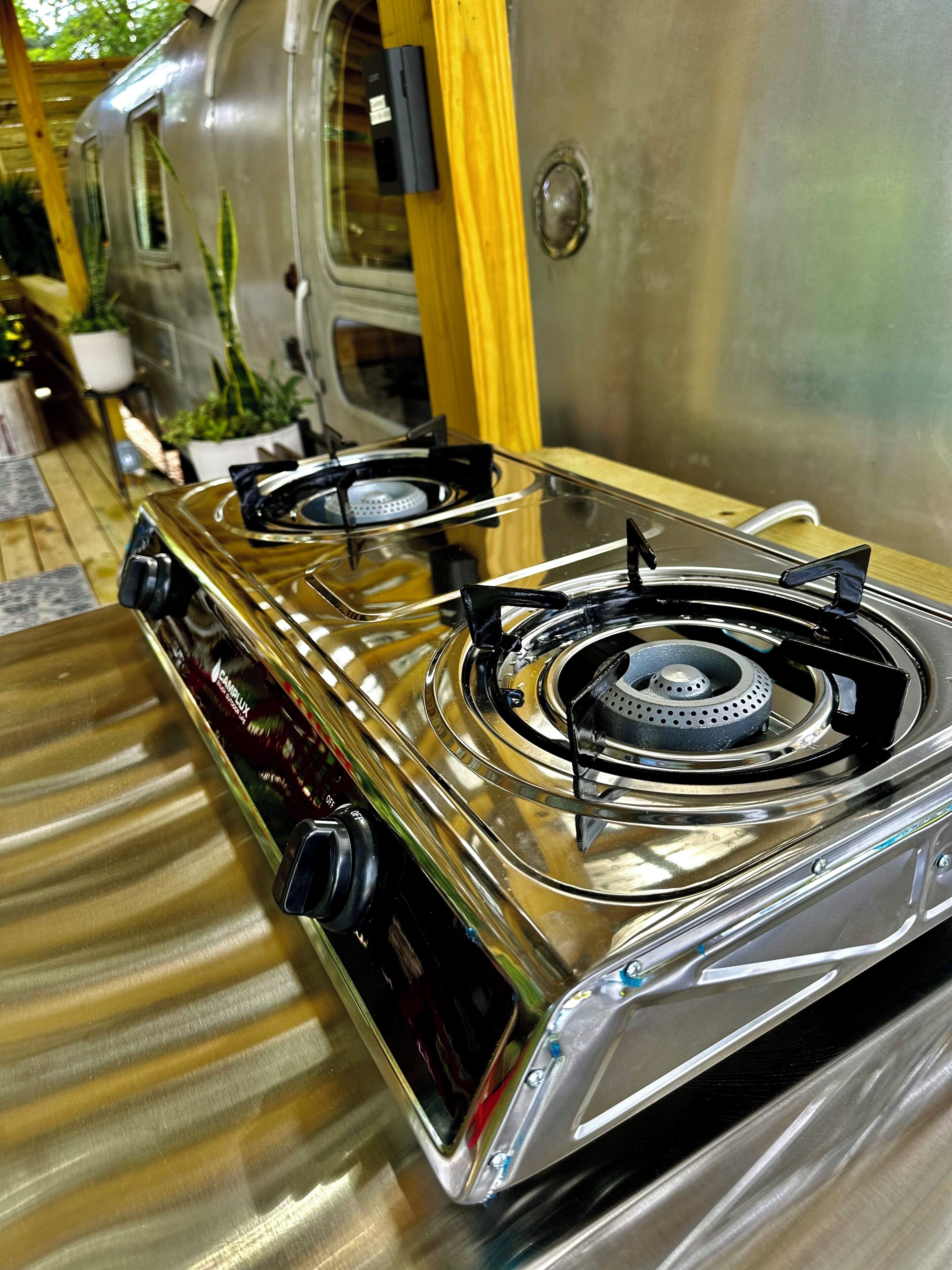 A stainless steel gas stove with four burners, a control knob, and a vent hood.