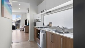 Een moderne keuken met een roestvrijstalen spoelbak, een magnetron en een fornuis. Er is een houten kast en een raam boven de spoelbak.