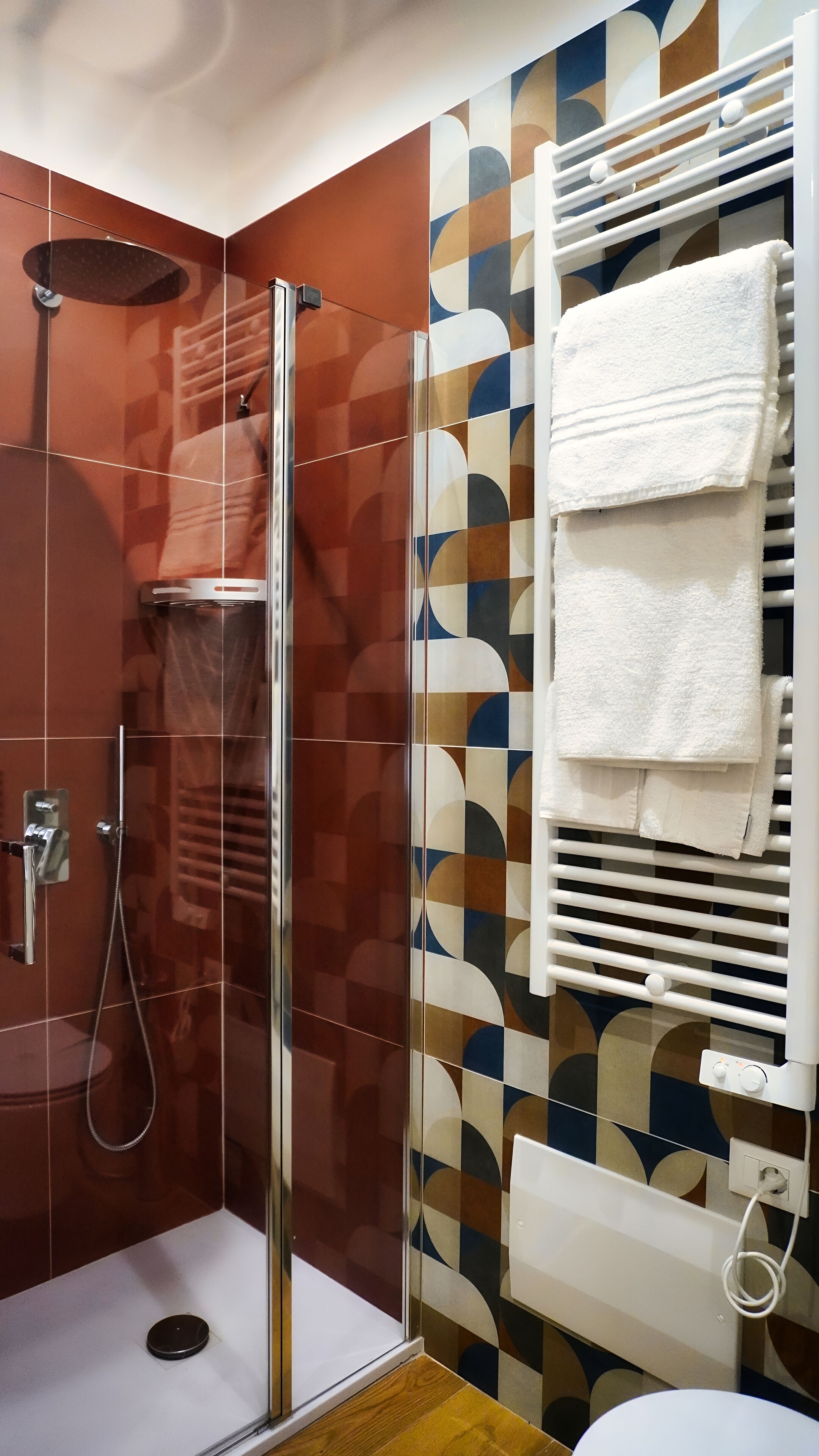 Ein modernes Badezimmer mit einer Duschkabine aus Glas, einer Toilette und einem Handtuchhalter mit Handtüchern.