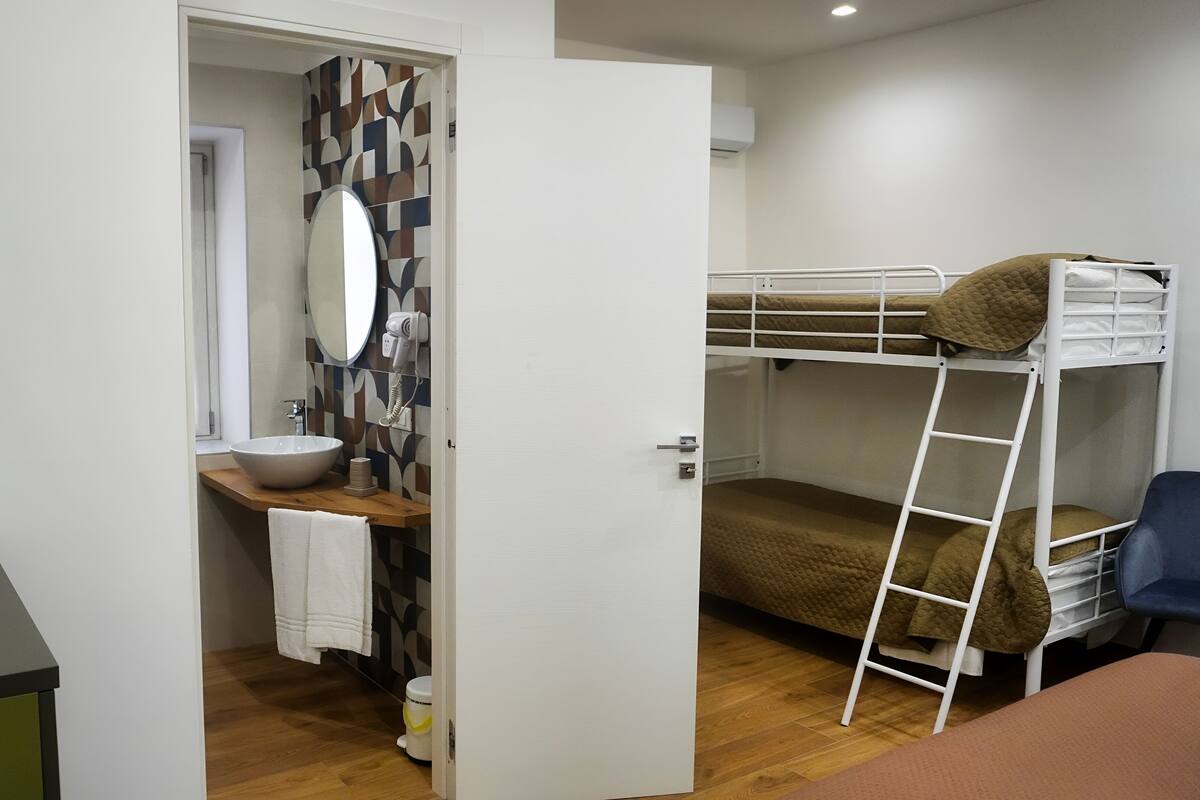 A compact room with a bunk bed, a small sink, and a mirror.