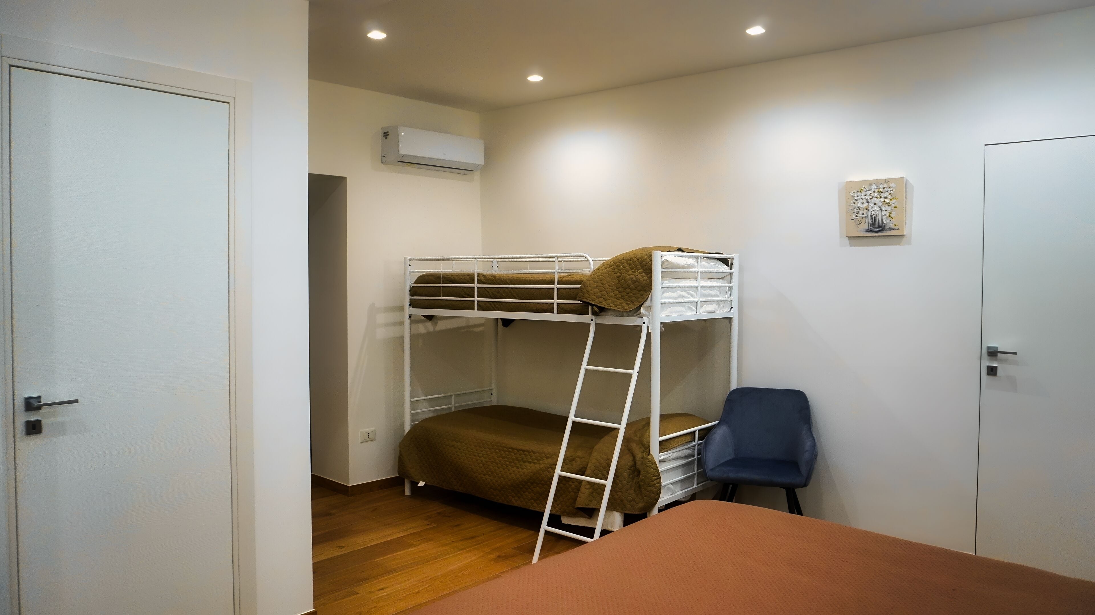 A bunk bed room with a ladder, a desk, and a chair.