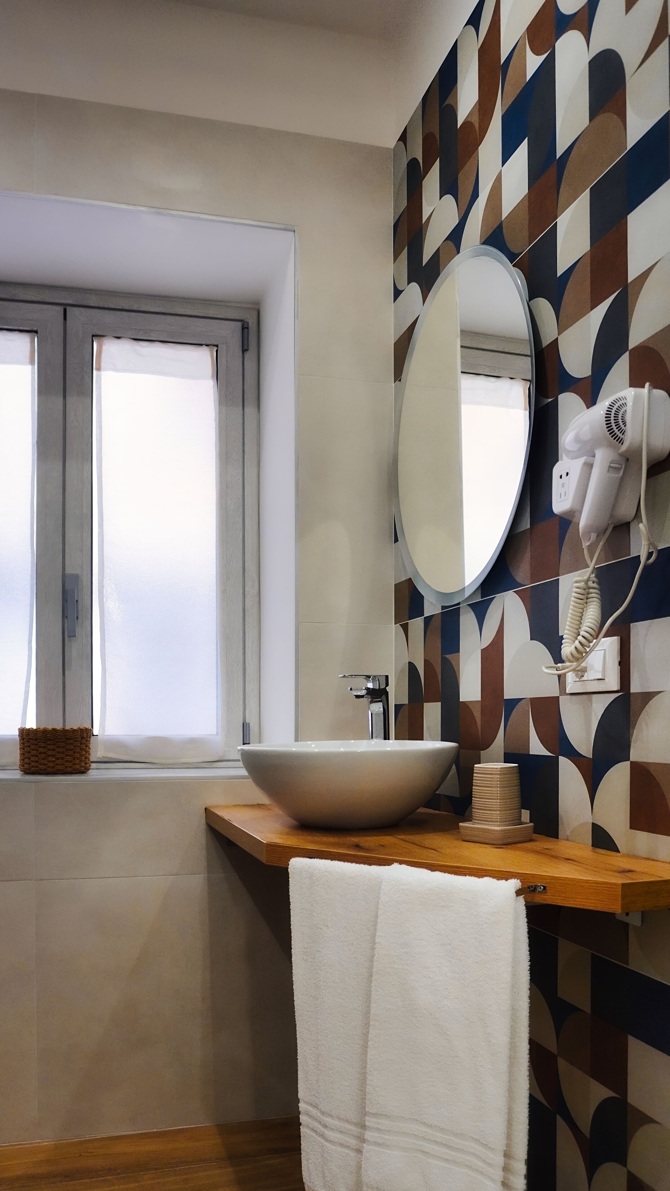 A bathroom with a large white sink, a mirror, and a hairdryer mounted on the wall.