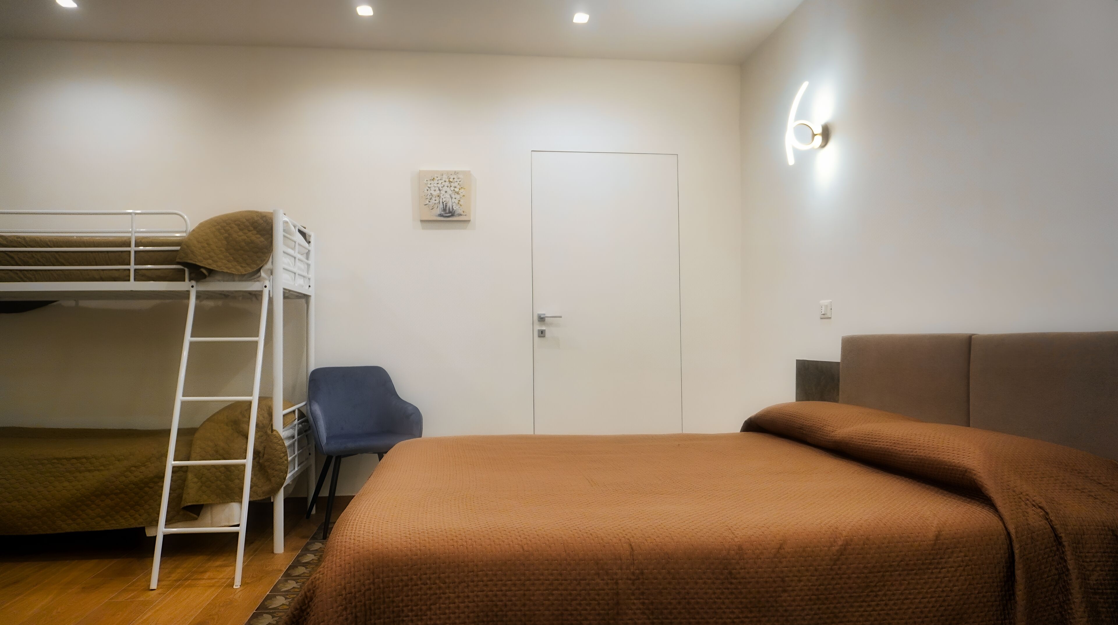A room with a bunk bed, a desk, a chair, and a sofa.