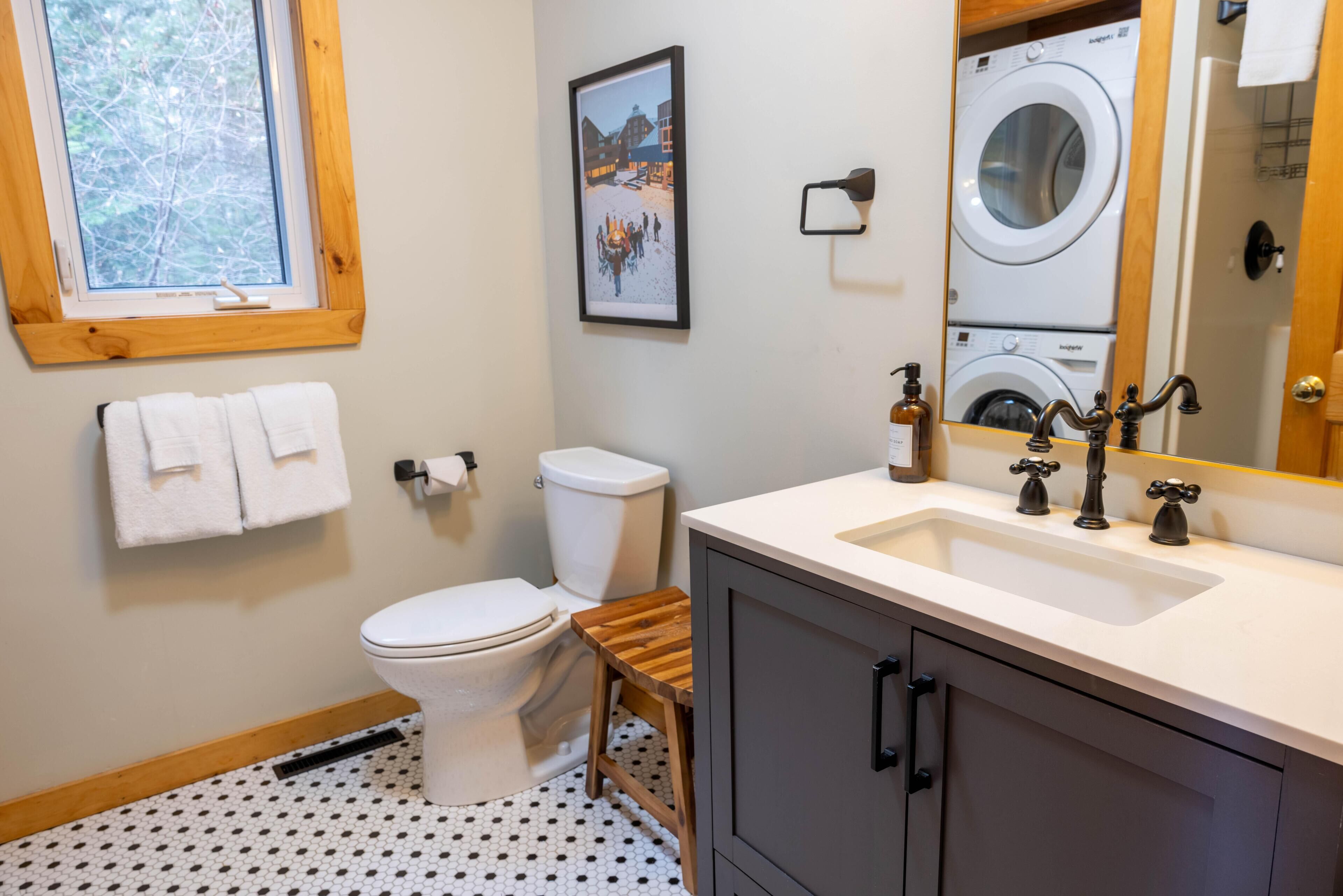 A bathroom with a toilet, sink, and a mirror reflecting a washing machine.
