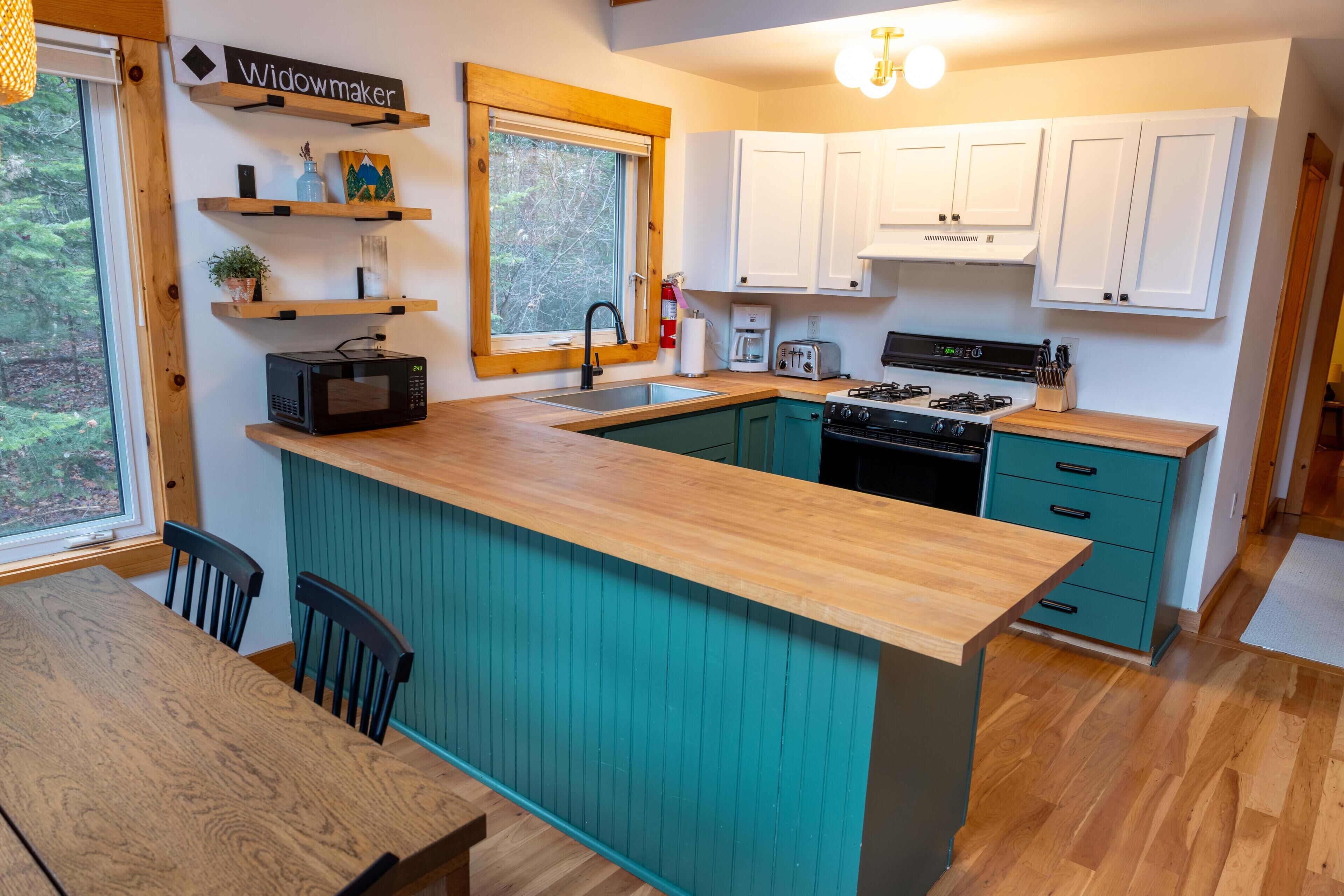 A modern kitchen with a wooden island, white cabinets, and a view of the outdoors.